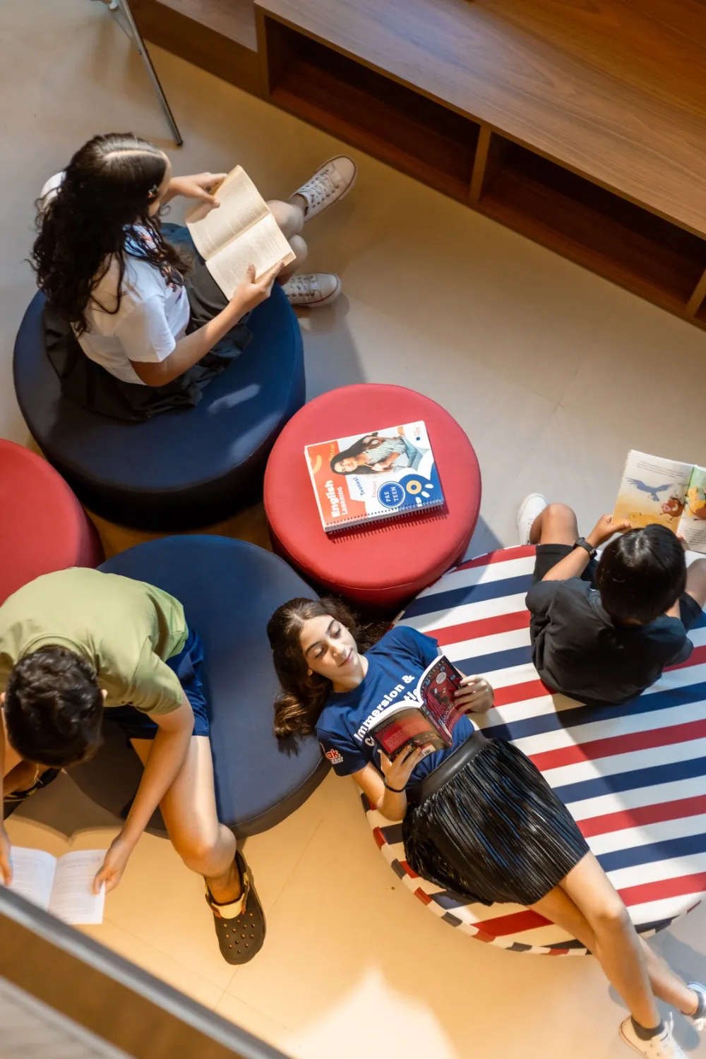 Adolescentes lendo em pufes coloridos na escola